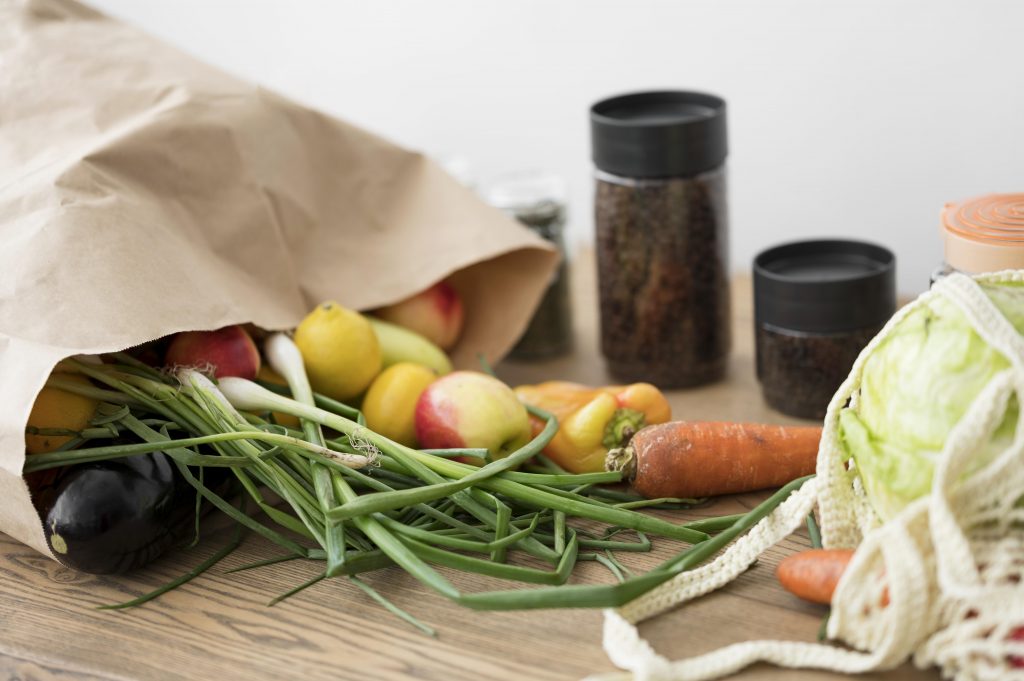 sac avec legumes et fruits sur table en bois